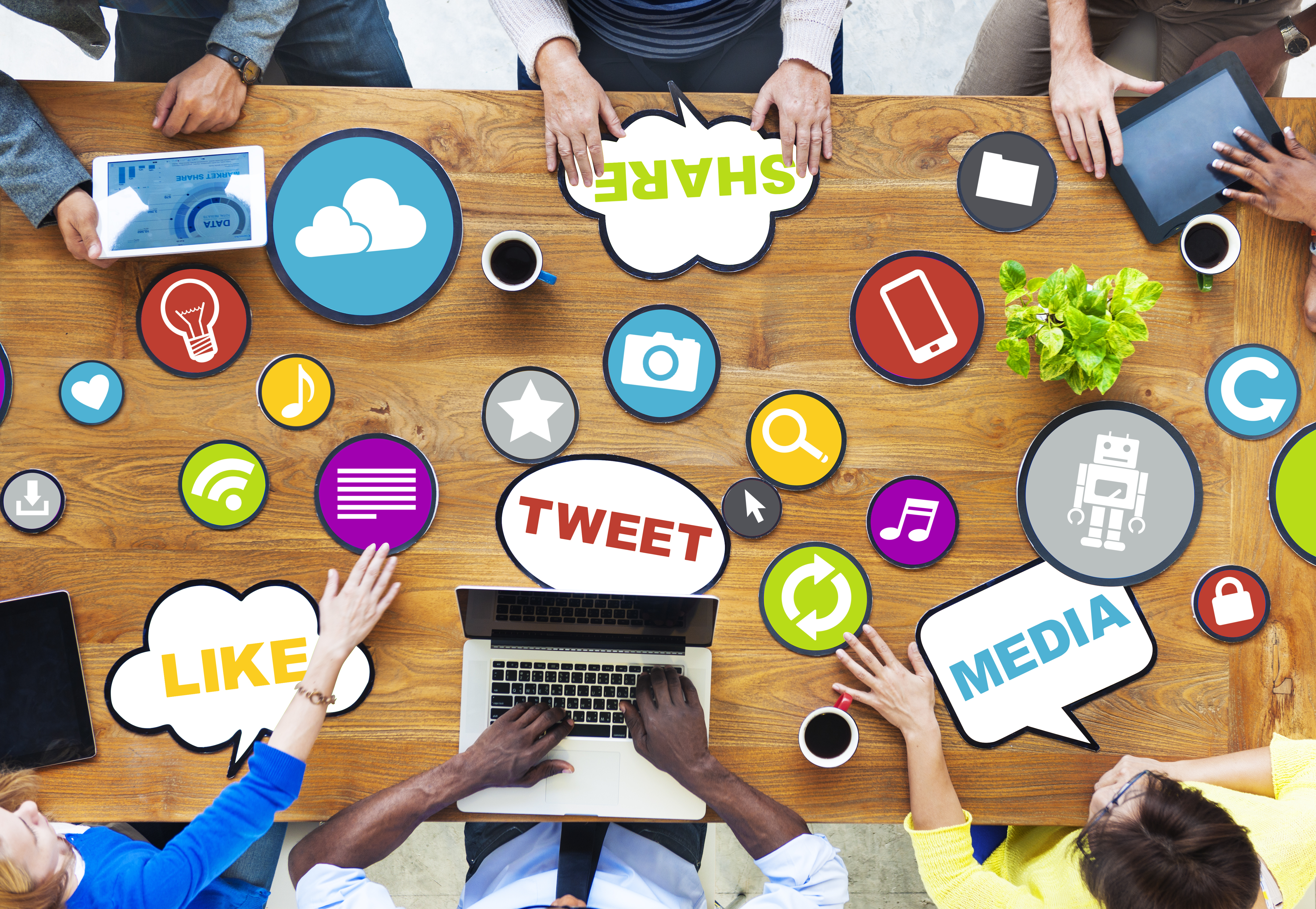 A group of people surrounding a table with social media icon and phrases on the table.